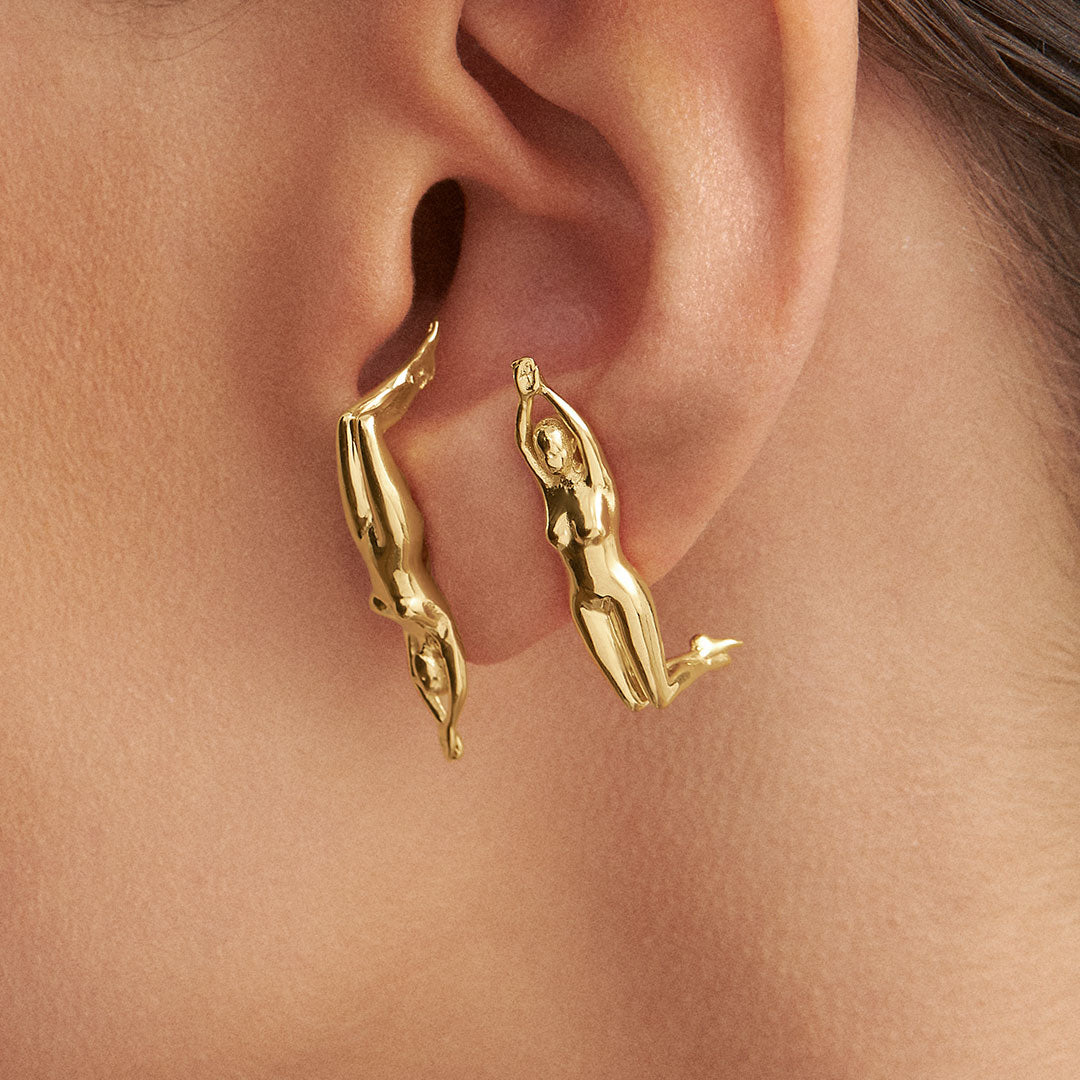 Modelo com brincos em prata 925 e banho de ouro 18k de corpo de mulher