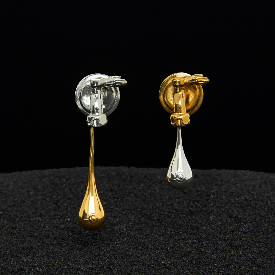 Paola Vilas O Brinco Mate Leoa faz uma releitura surrealista e feminina do Mate Leão, bebida simbólica das praias cariocas. As torneiras são recriadas trazendo padrões de curvas e abridores em formato de mãos. Gotas pingam se tornando seios. Joias femininas.