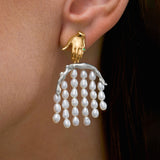 Modelo usando brinco em prata 925 e banho de ouro 18k de mão e corpo adornado com pérolas e esmeralda