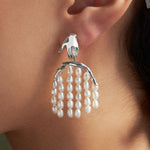 Modelo usando brinco em prata 925 de mão e corpo feminino adornado com pérolas e esmeralda