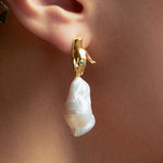 Modelo usando brinco de mão em prata 925 com banho de ouro 18k, esmeralda e pérola barroca