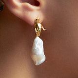 Modelo usando brinco de mão em prata 925 com banho de ouro 18k, esmeralda e pérola barroca