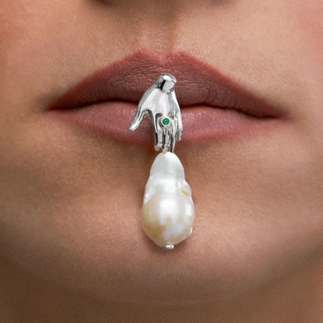 Modelo usando brinco de mão em prata 925, esmeralda e pérola barroca