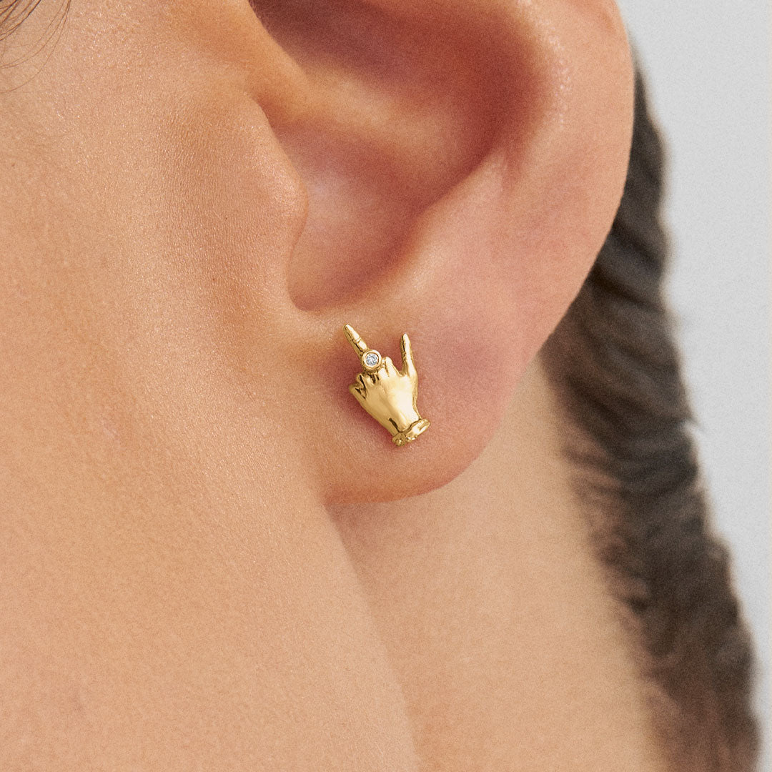 Modelo usando brinco em ouro 18k de mini dedo do meio adornado com diamante