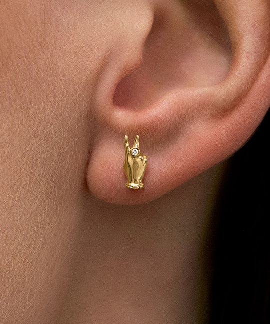 Modelo usando brinco em ouro 18k de mini mão em sinal de paz com diamante
