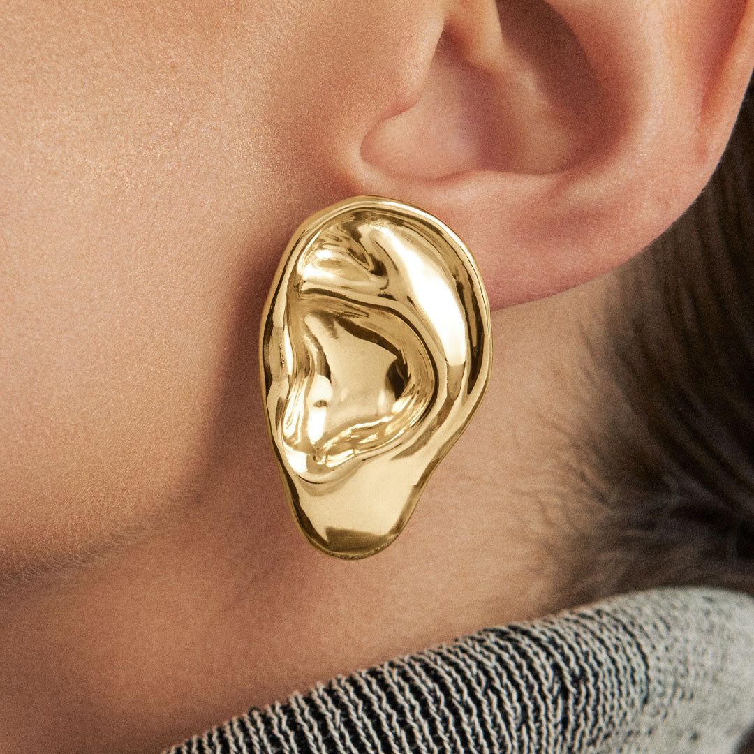 Modelo usando brinco em prata 925 com banho de ouro 18k de orelha esculpida