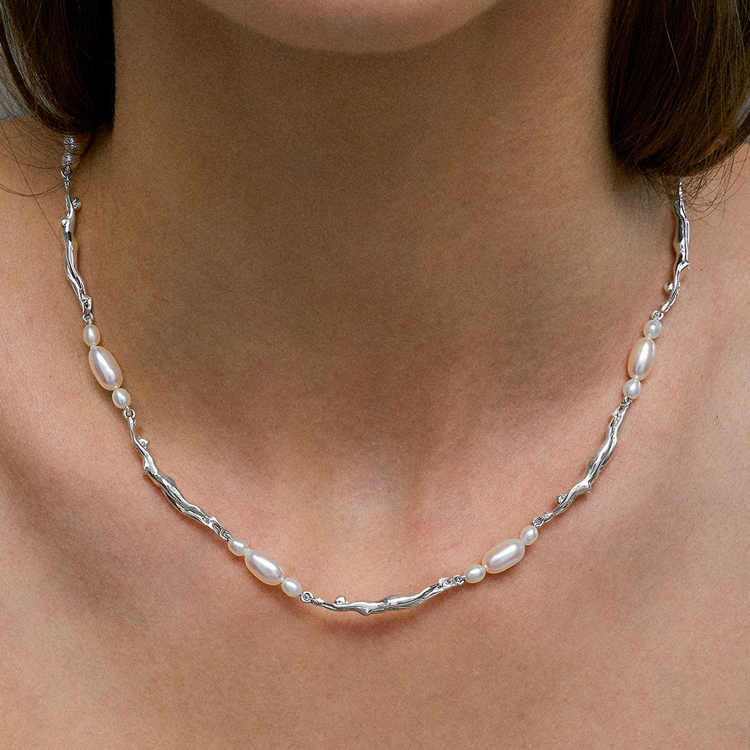 Modelo usando colar de corpos femininos em prata 925 e pérolas adornado com esmeralda