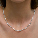 Modelo usando colar de corpos femininos em prata 925 e pérolas adornado com esmeralda