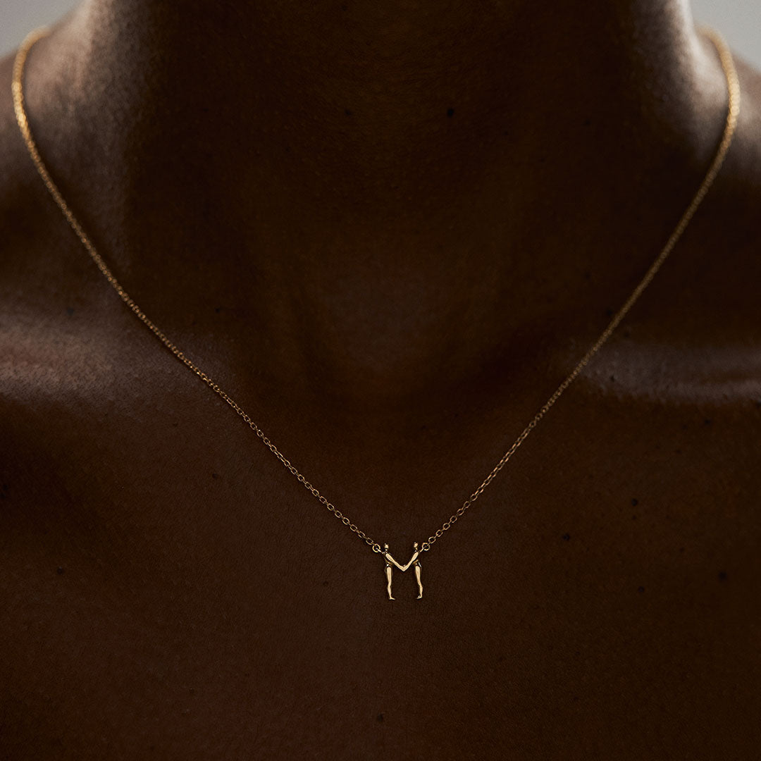 Modelo usando colar em ouro 18k de letra do alfabeto em forma de corpos femininos