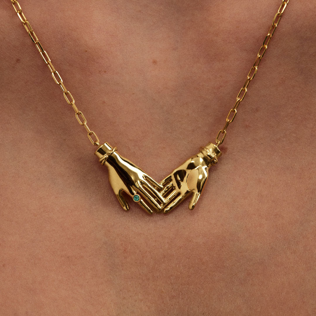 Modelo usando colar em prata 925 com banho de ouro 18k de mãos dadas adornado com esmeralda