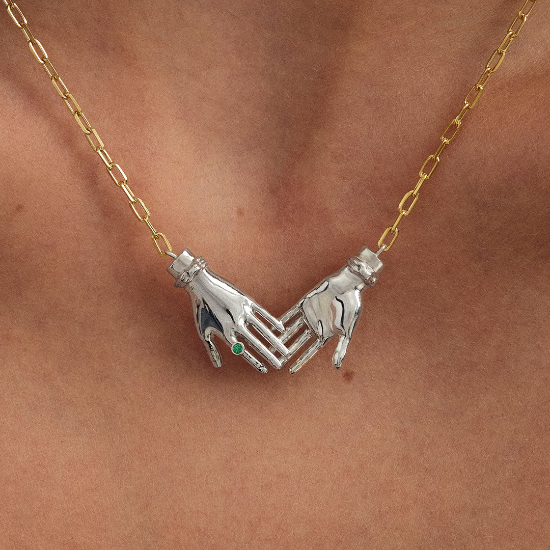 Modelo usando colar em prata 925 com corrente banhada em ouro 18k de mãos dadas adornado com esmeralda