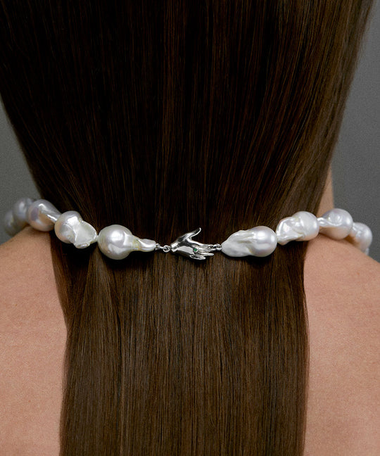 Modelo usando colar de pérolas barrocas com fecho de mão em prata 925 e esmeralda