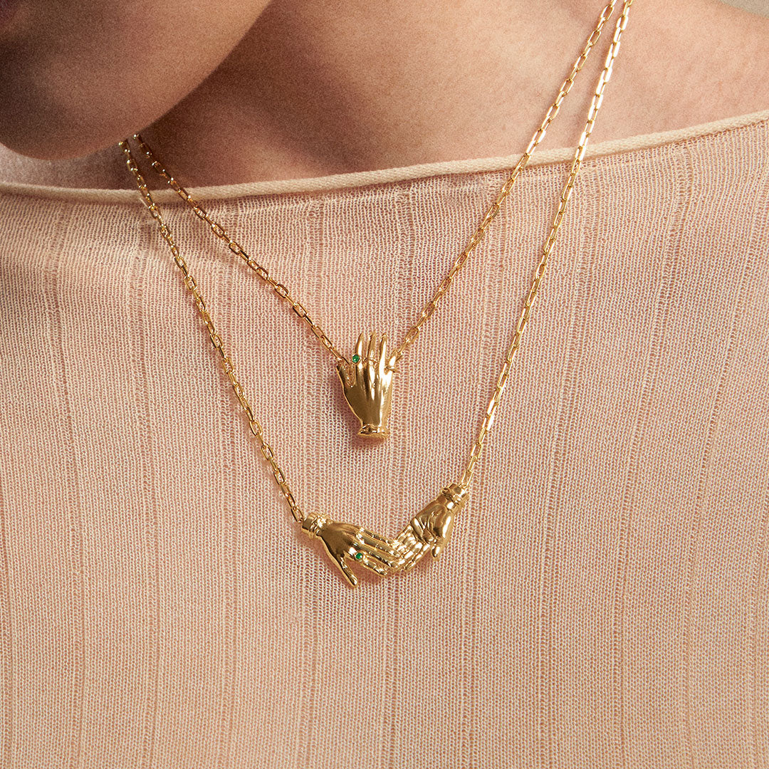 Modelo usando colares em prata 925 e banho de ouro 18k de mãos adornadas de esmeraldas