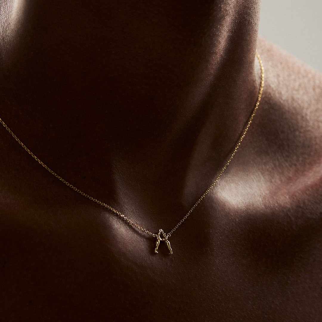 Modelo usando colar em ouro 18k de inicial personalizável com letra em forma de corpos femininos