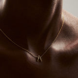 Modelo usando colar em ouro 18k de inicial personalizável com letra em forma de corpos femininos