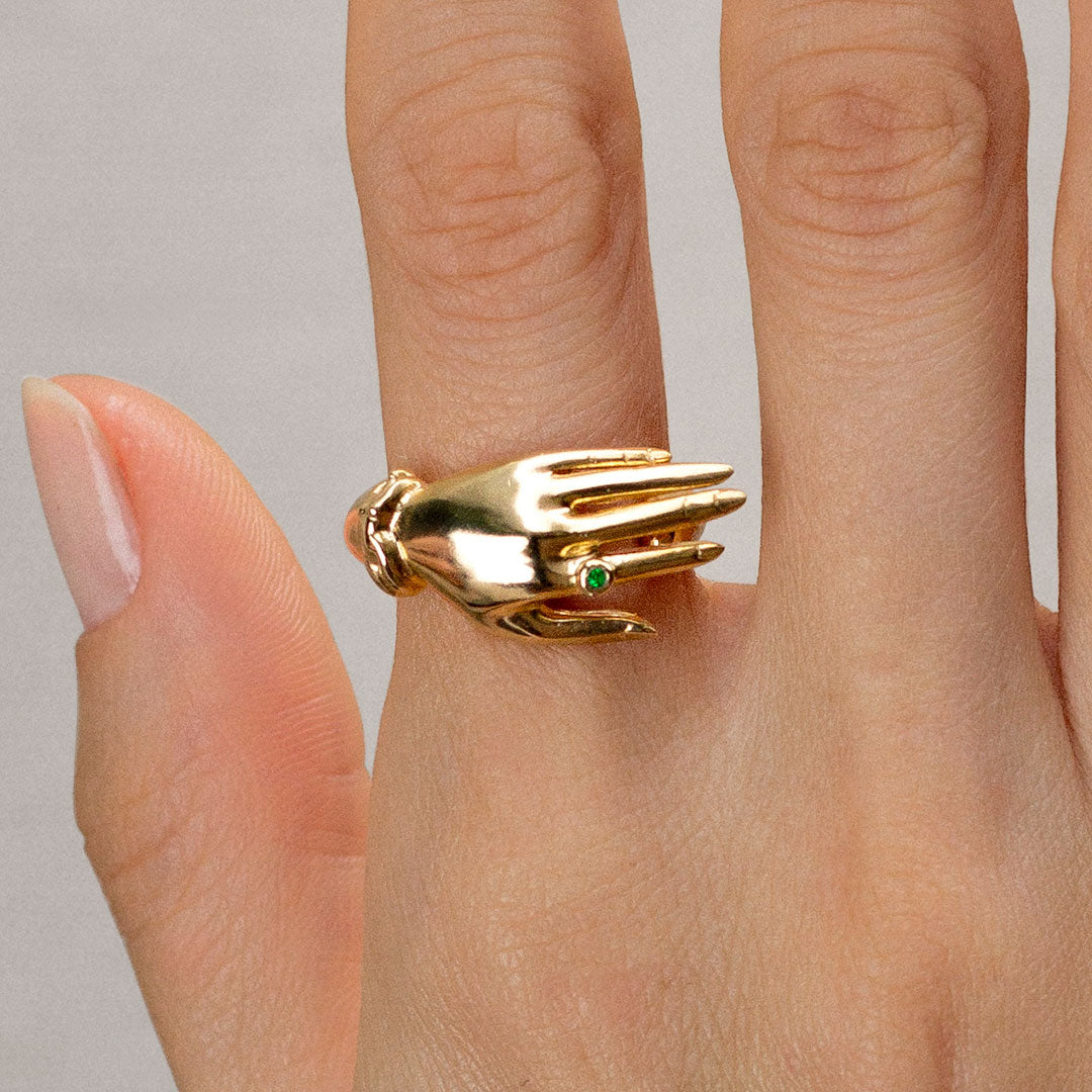Modelo com anel em prata 925 e banho de ouro 18k de mão com esmeralda