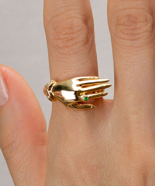 Modelo com anel em prata 925 e banho de ouro 18k de mão com esmeralda