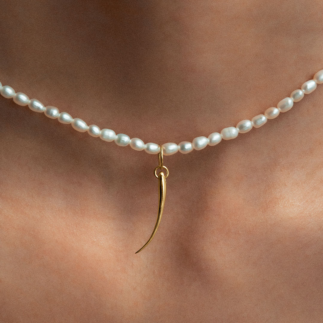 Modelo usando pendente em ouro 18k de cílio em colar de pérolas