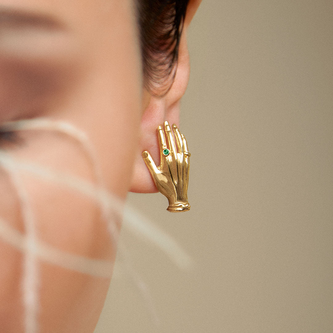 Modelo usando brinco de mão em prata 925 com banho de ouro 18k e esmeralda
