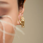 Modelo usando brinco de mão em prata 925 com banho de ouro 18k e esmeralda